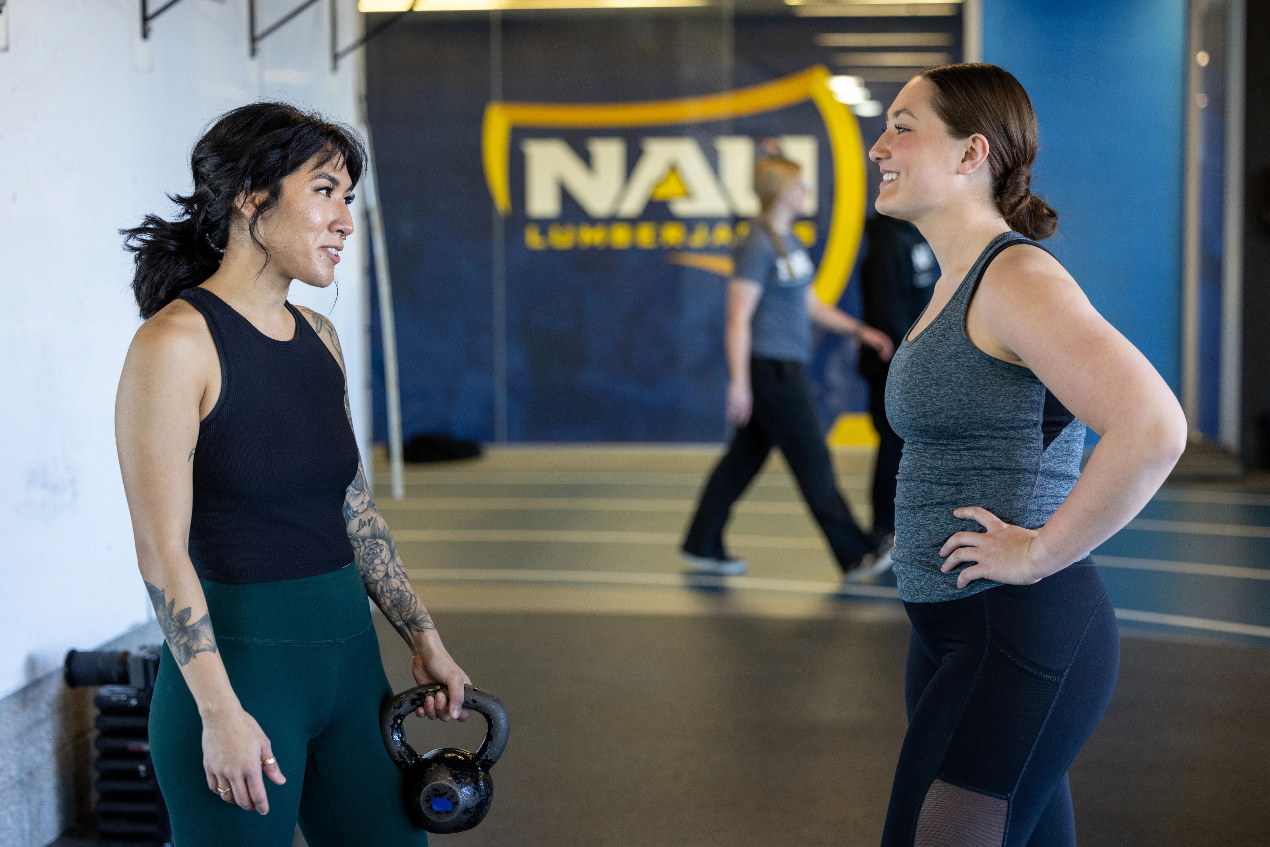 Two students talking to each other in the gym.