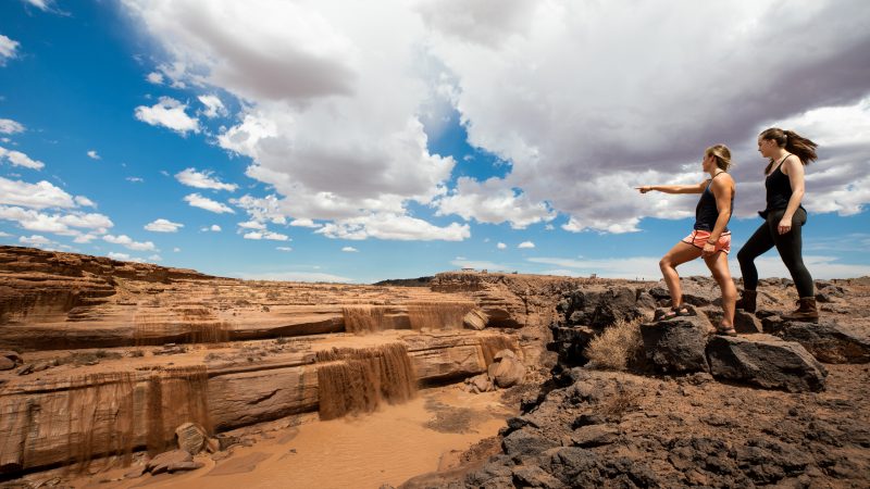 Two hikers at Grand Falls pointing at small mud waterfalls.