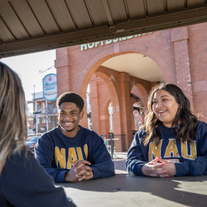 Students sit together downtown wearing NAU sweatshirts