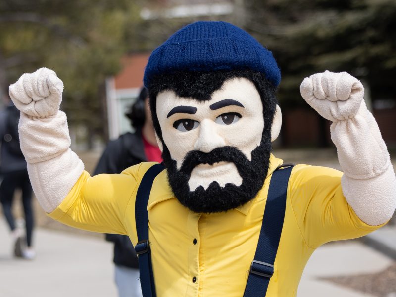 Louie the Lumberjack stands near the bike path at NAU in a victory stance&mdash;with his fists up in the air.
