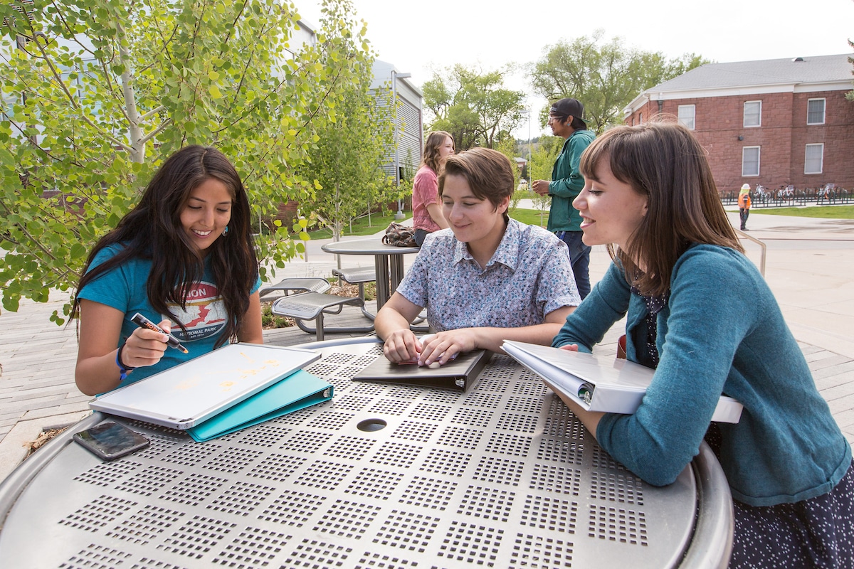 Students working on class work at a table outside.
