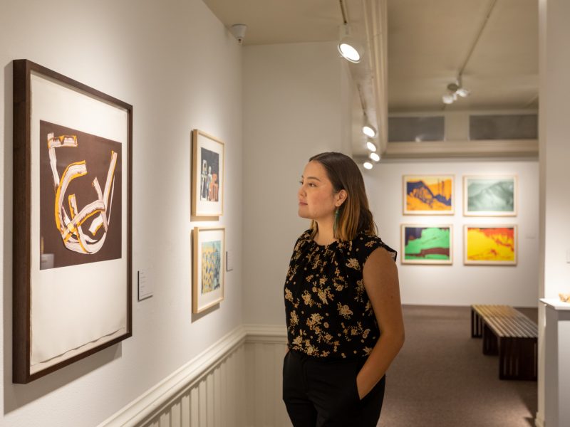 A student looking at artwork on a wall.
