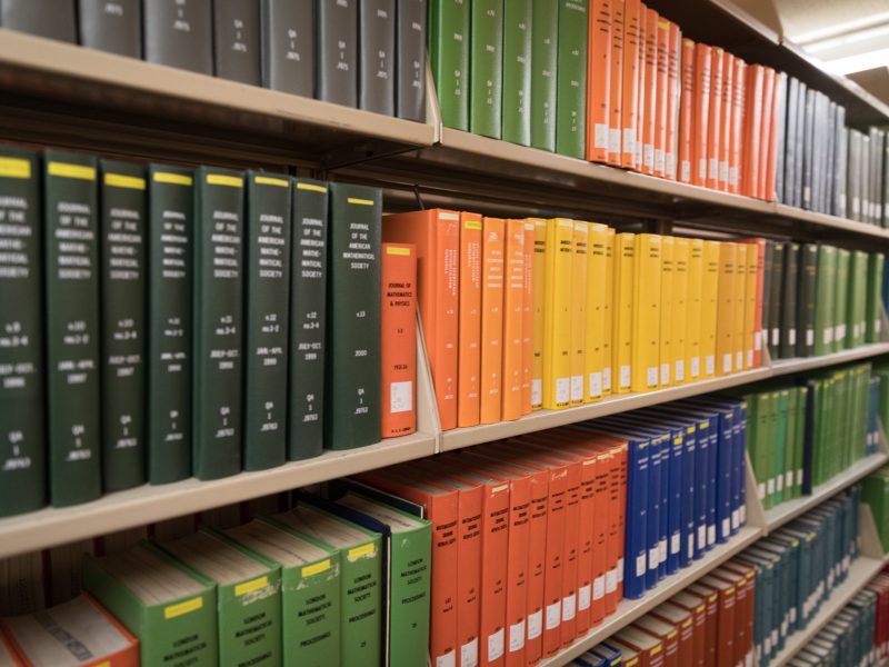 Different colored books on bookshelves.