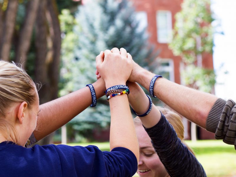 People holding hands with N A U Strong bracelets on.