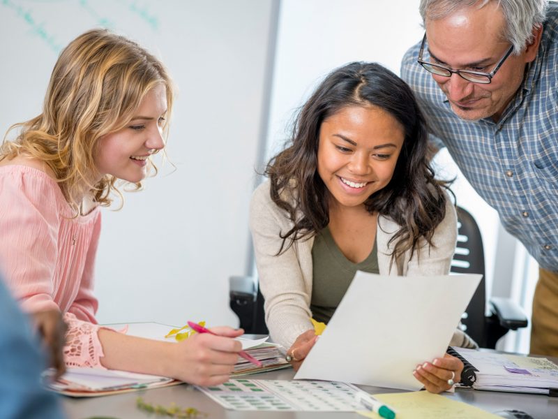 Students and their professor looking at an assignment.