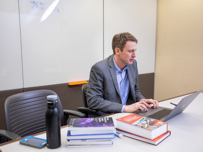 Professor works on laptop in a conference room.