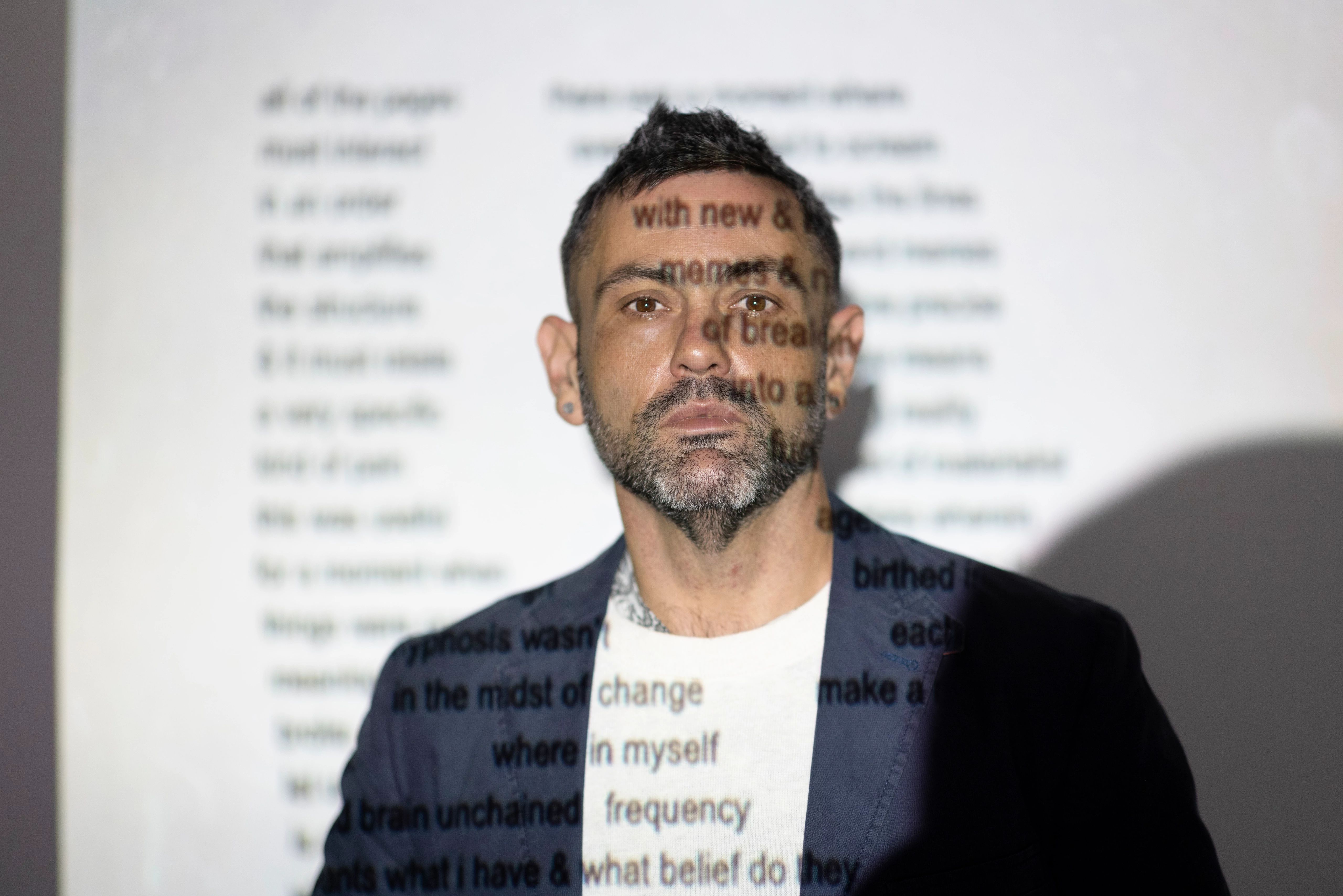 Professor stands in front of projector and looks at camera.