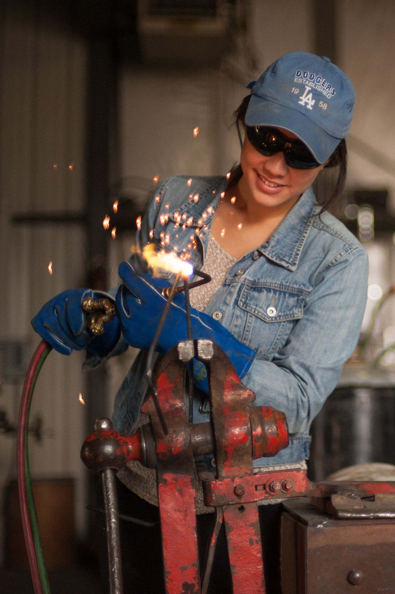 Student welds sculpture with safety glasses.