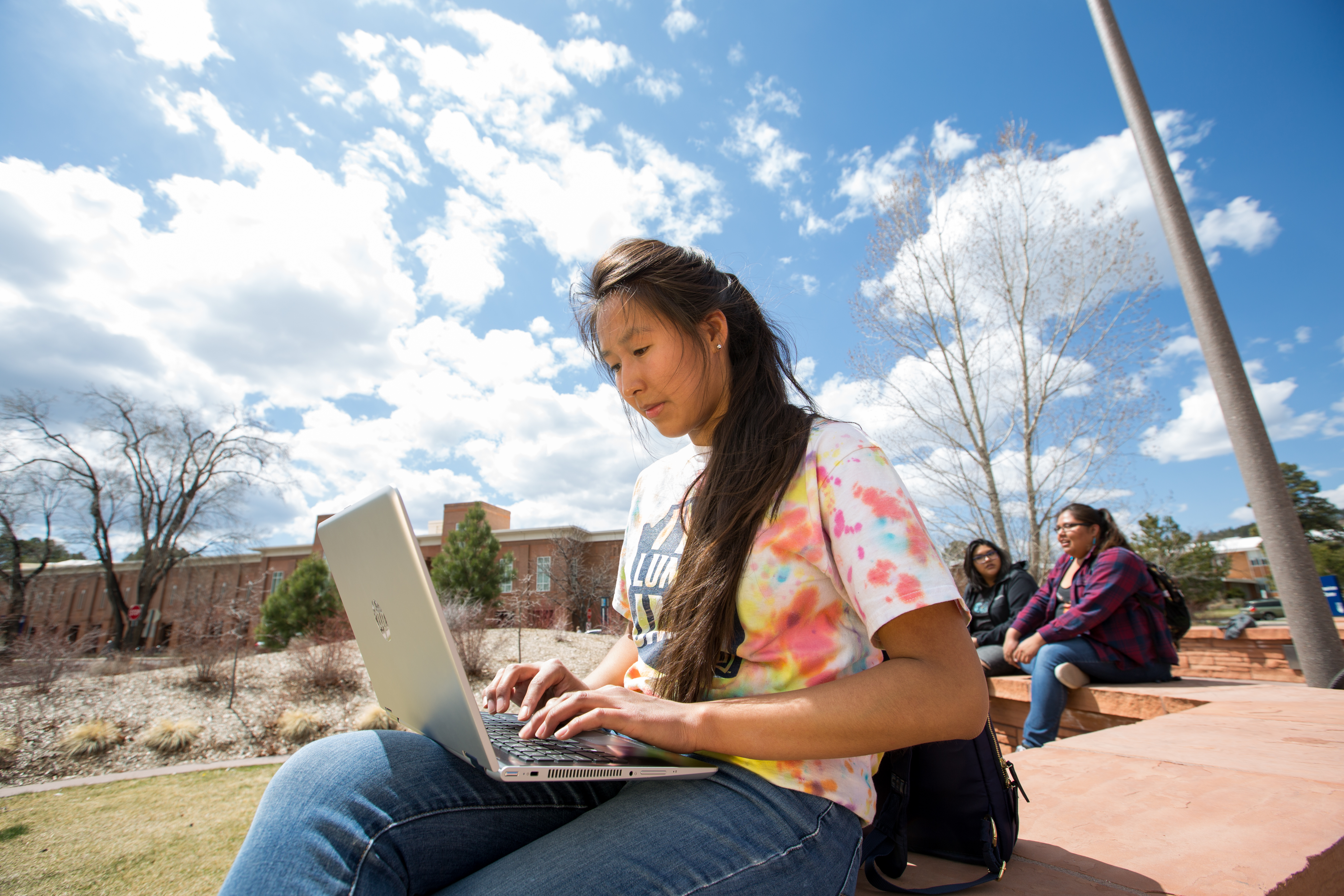 Student works on laptop outside.