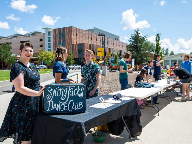 Students stand in front of Swing Jacks Dance Club table. outside smiling.