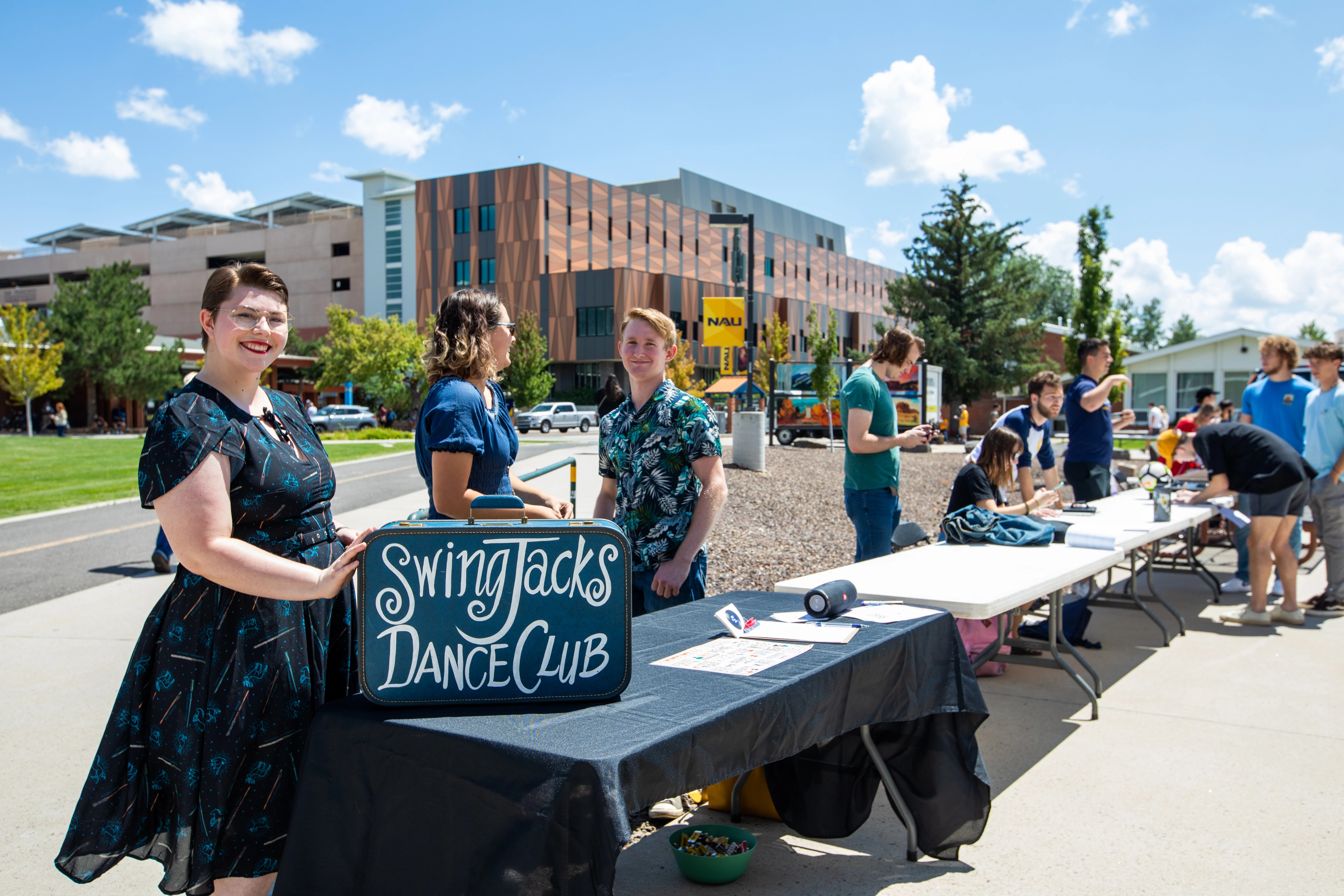 Students stand in front of Swing Jacks Dance Club table. outside smiling.
