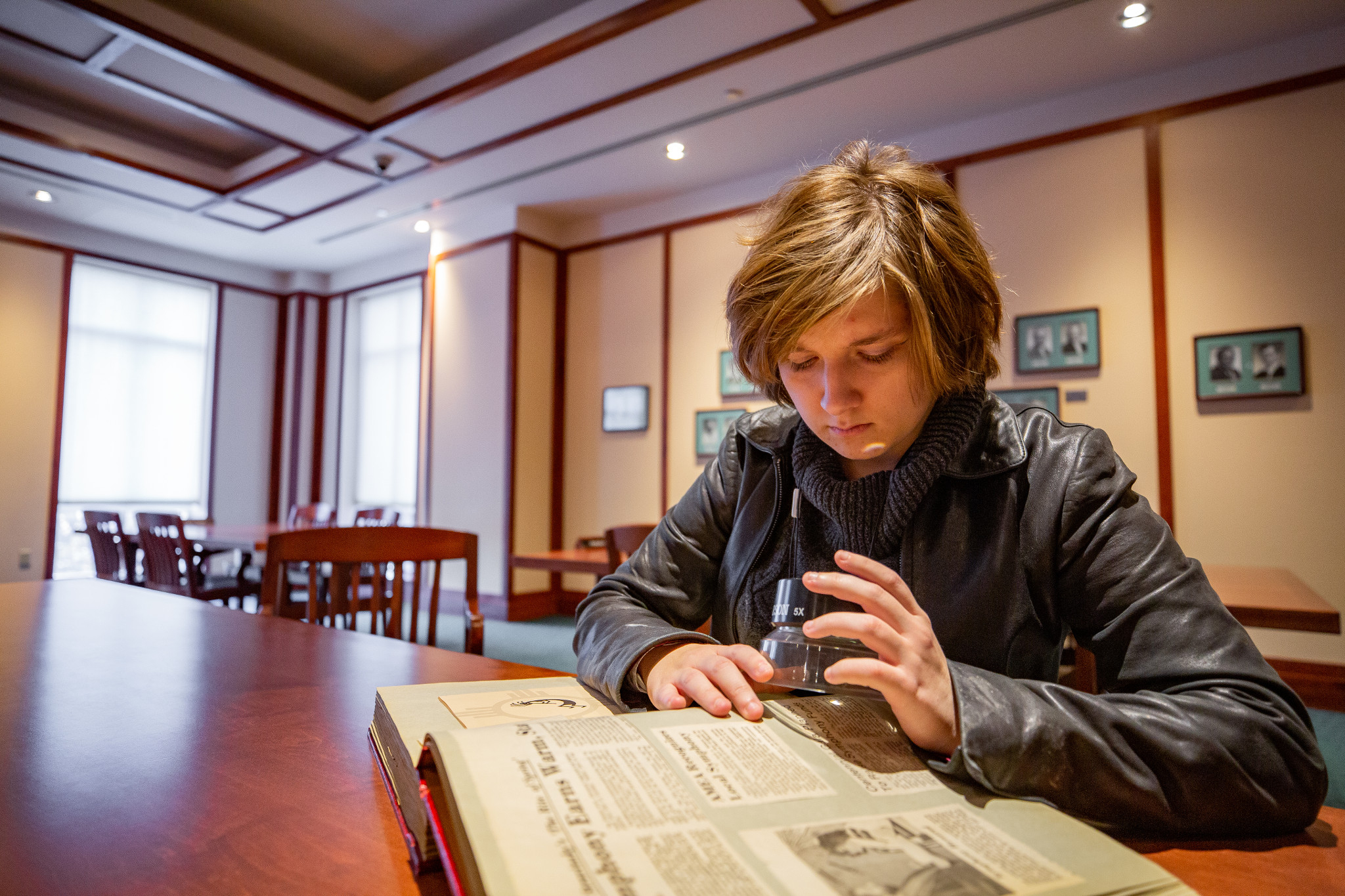 Student reads historic book with microscope.
