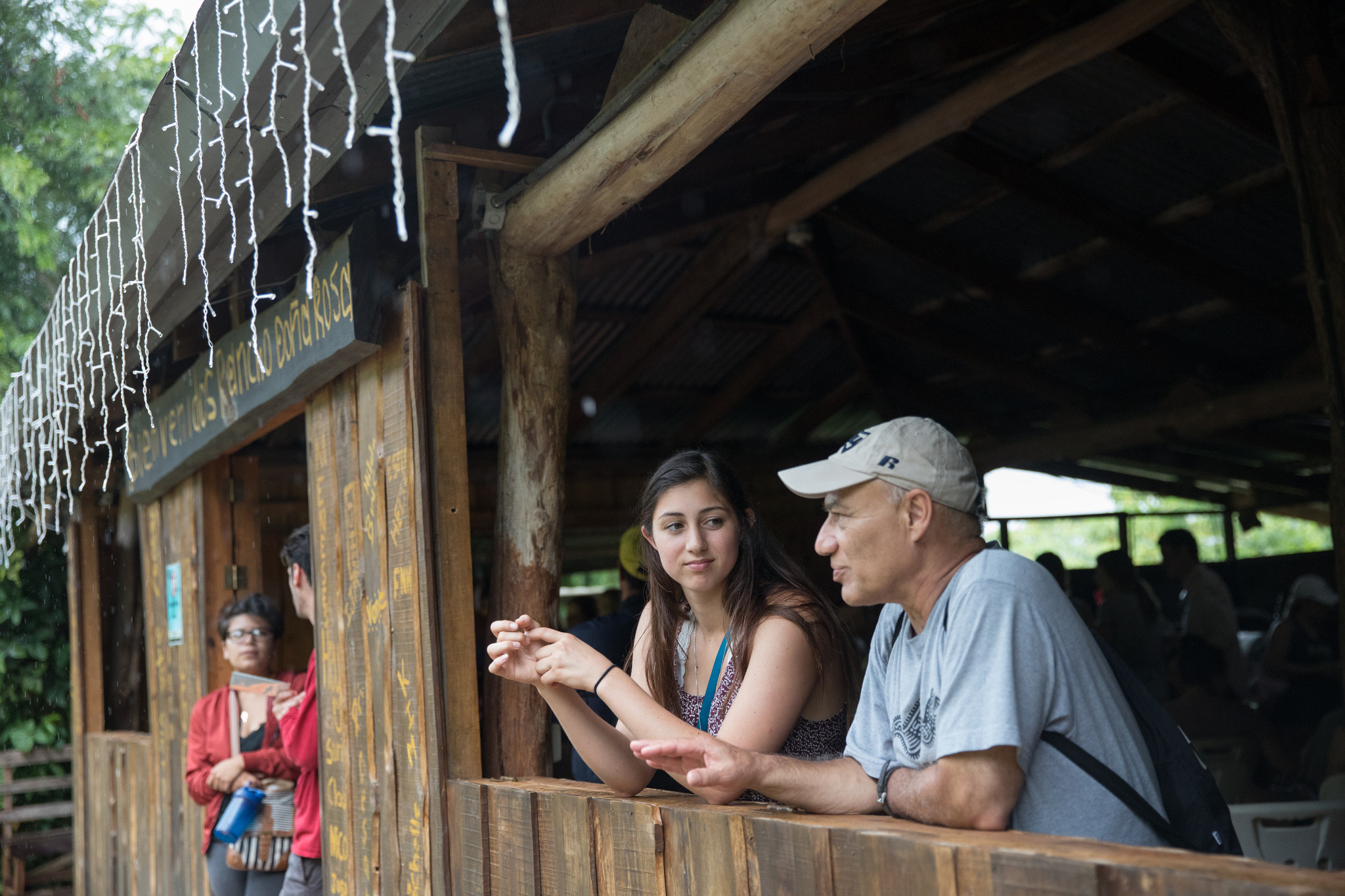 Instructor and student talking while leaning on wooden wall of a ramada.