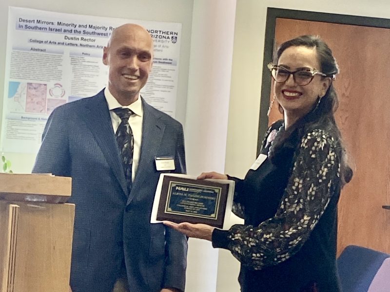Alicia Yazzie Summers accepts their award from Dean Boyer the morning of commencement in the Riles Building.