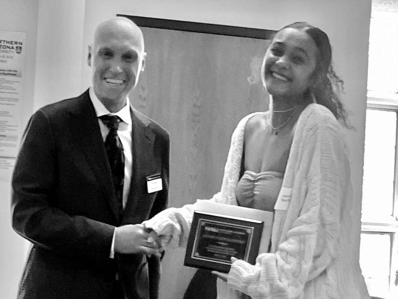 Jaz accepts their award from Dean Boyer on the morning of commencement in the Riles Building.
