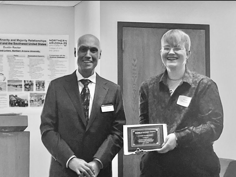Asher Robinson accepts their award from Dean Boyer on the morning of Commencement in the Riles Building