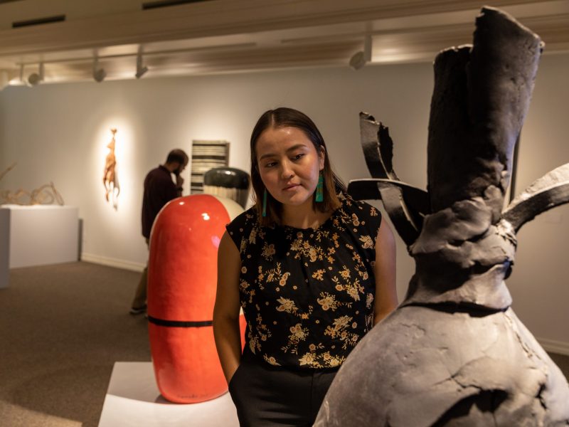 An art curator examining a sculpture in a gallery.