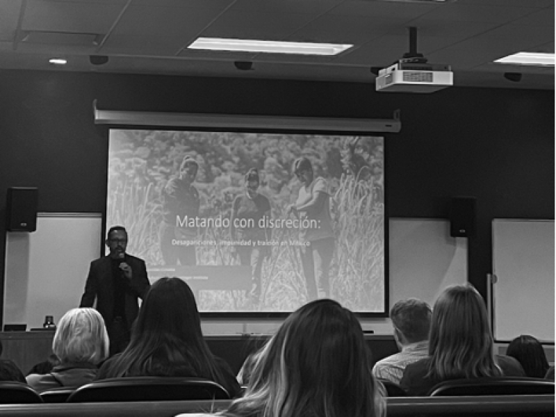Instructor teaching Spanish class in front of projection screen.