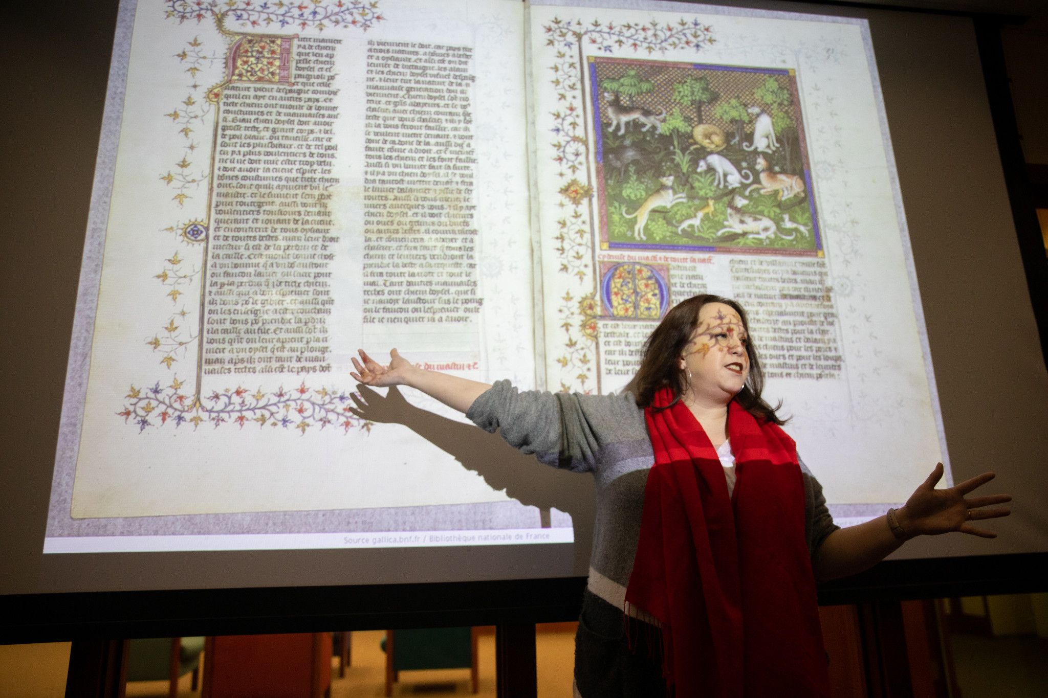 Teacher wearing red scarf presenting a powerpoint on medieval text.