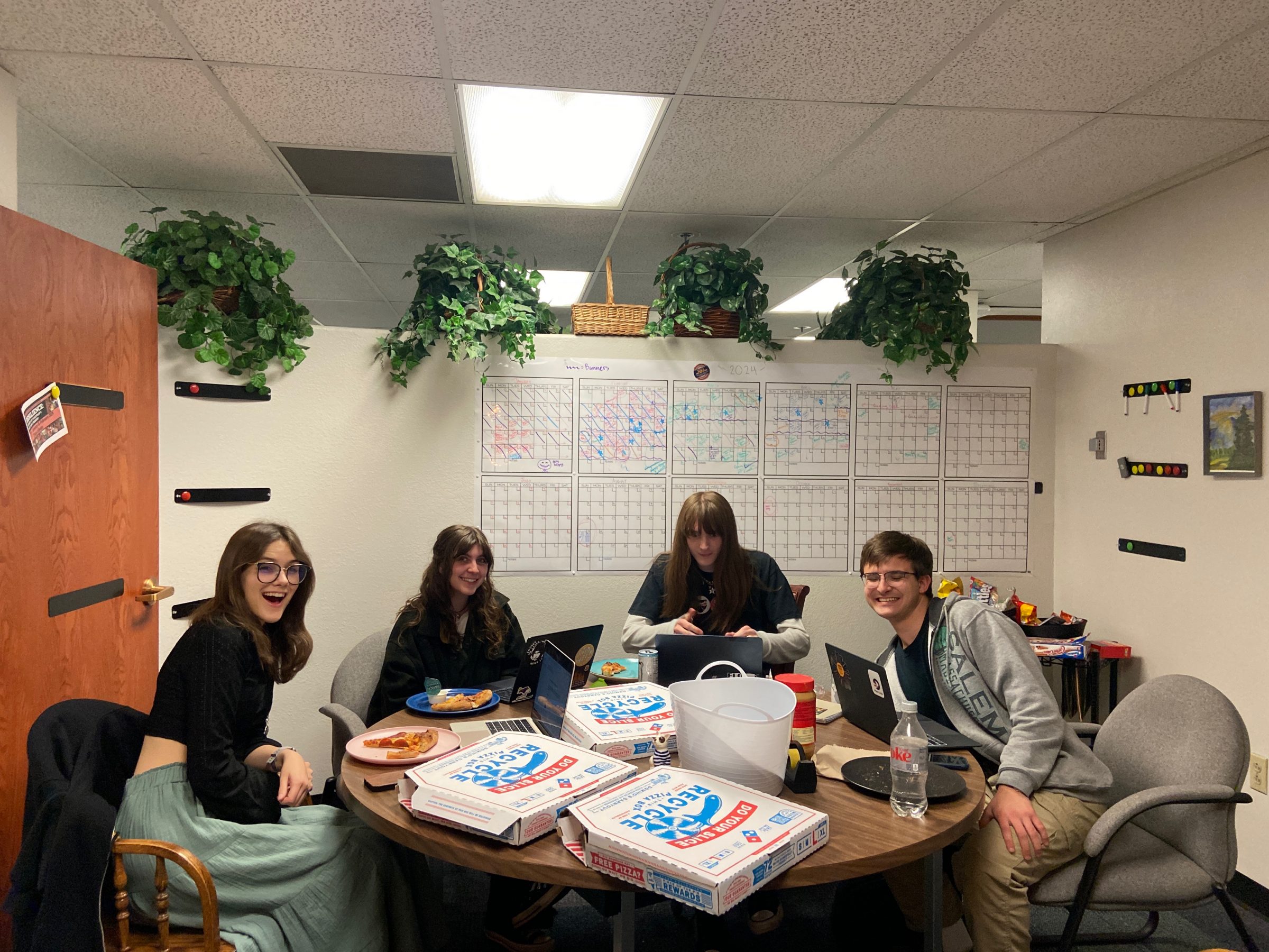 Four students working together at a table and smiling.