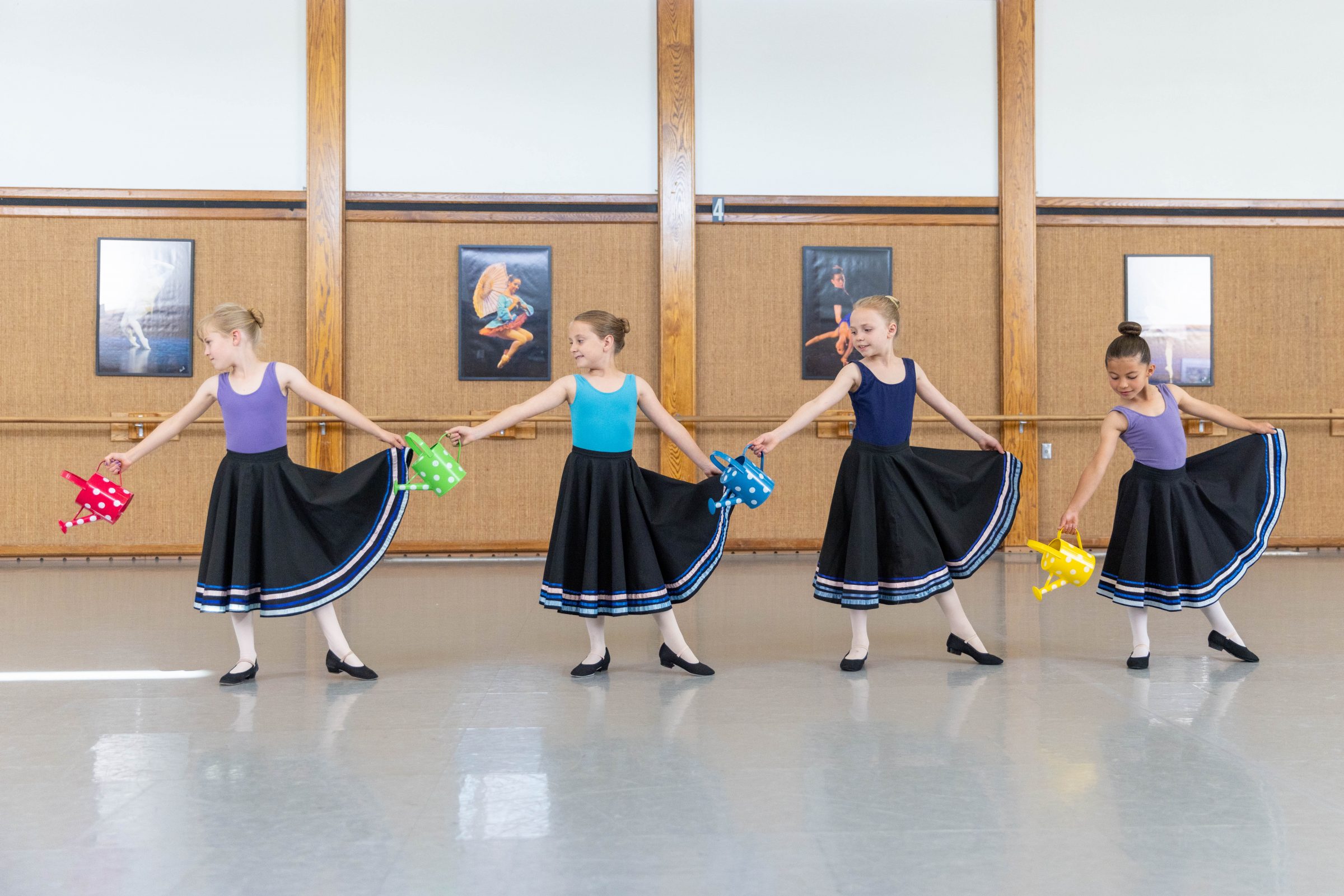 Group of four ballerinas holding watering cans.