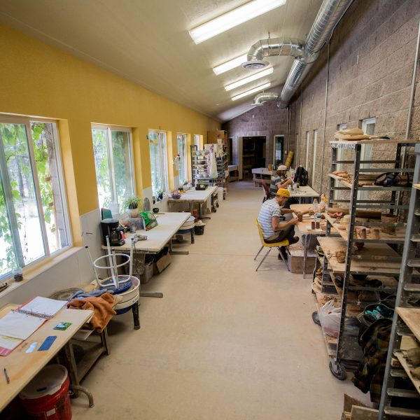 A long hallway filled with ceramics workstations and projects.