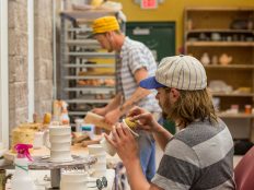 Students in a ceramics class shaping mugs.
