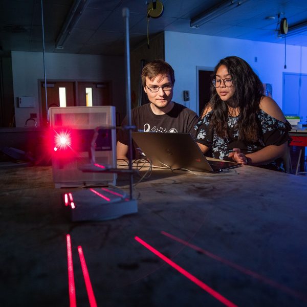 Two student working with lasers at a laptop.