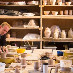 Professor helping students through their ceramic-making projects.