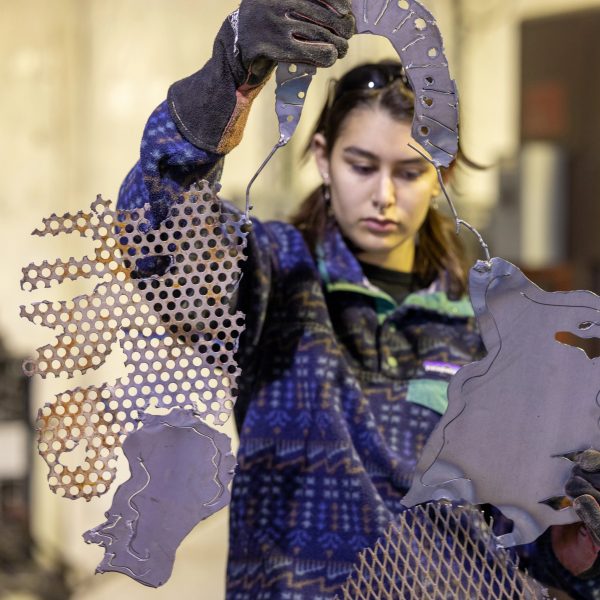 Student holding up a metal sculpture that she made.