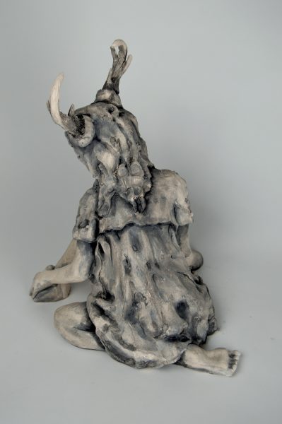 Back view of a sculpture of a humanoid figure with antlers.