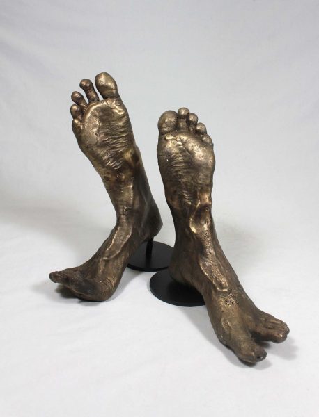 Sculptures of bronze human feet in heel toe formation.
