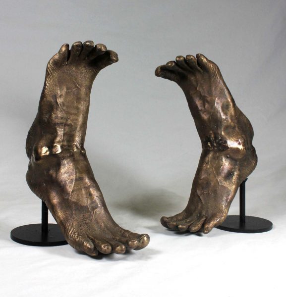 Sculptures of bronze human feet in heel toe formation.