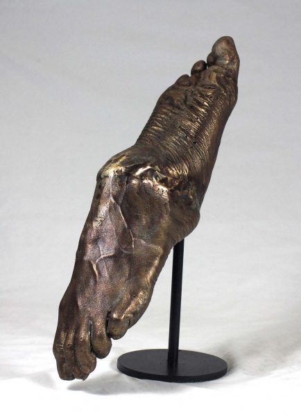 Sculpture of bronze human feet in a see saw formation.