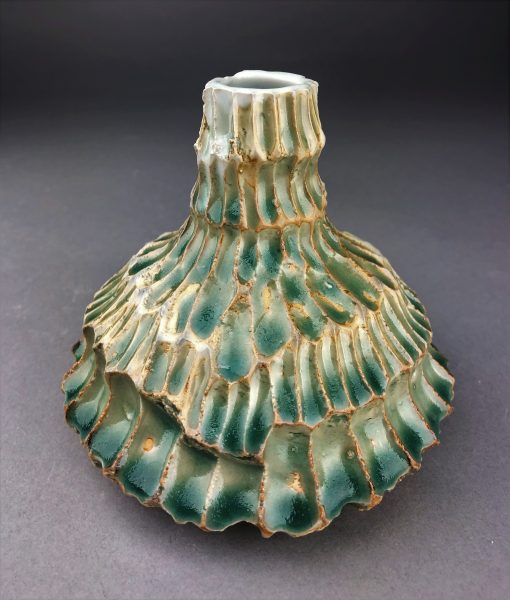 A teal, scaled, ceramic sculpture called "Sea."