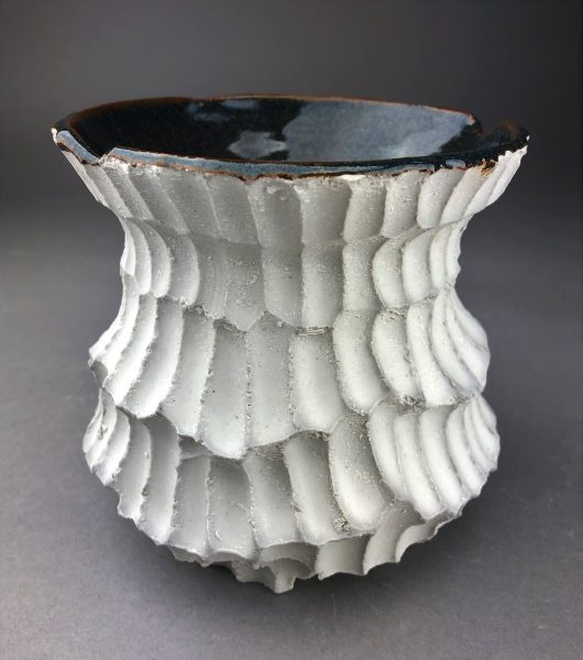 A white, scaled, ceramic bowl sculpture called "Snow."