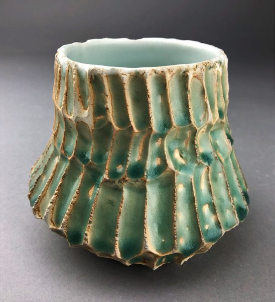 A teal, scaled, ceramic bowl-like sculpture called "Marine."