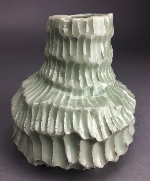 A green scaled, ceramic elongated bowl sculpture.
