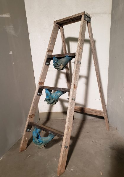 A ladder with blue hand sculptures attached to the bottom of the rungs.