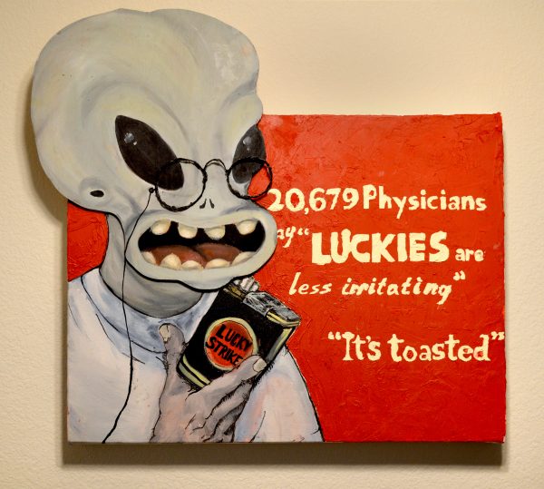 Wall art with an alien holding a container of Lucky Strike.