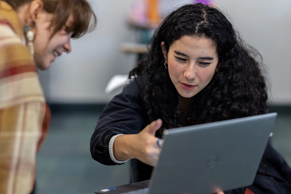 Students collaborating behind a laptop in class.
