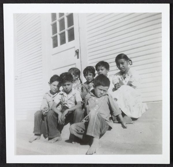 A group of farmworker children seated together outdoors.