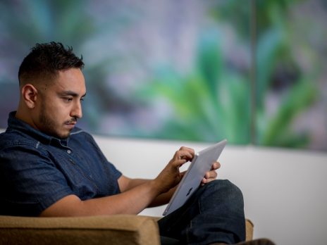 A mature student in a chair using a device.