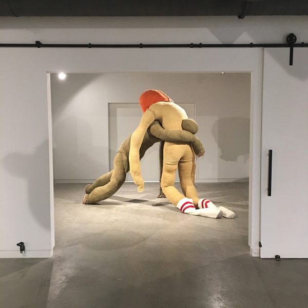 Soft sculpture of two intertwined anamorphic figures. Made from handwoven fabric, used clothing, steel, zippers