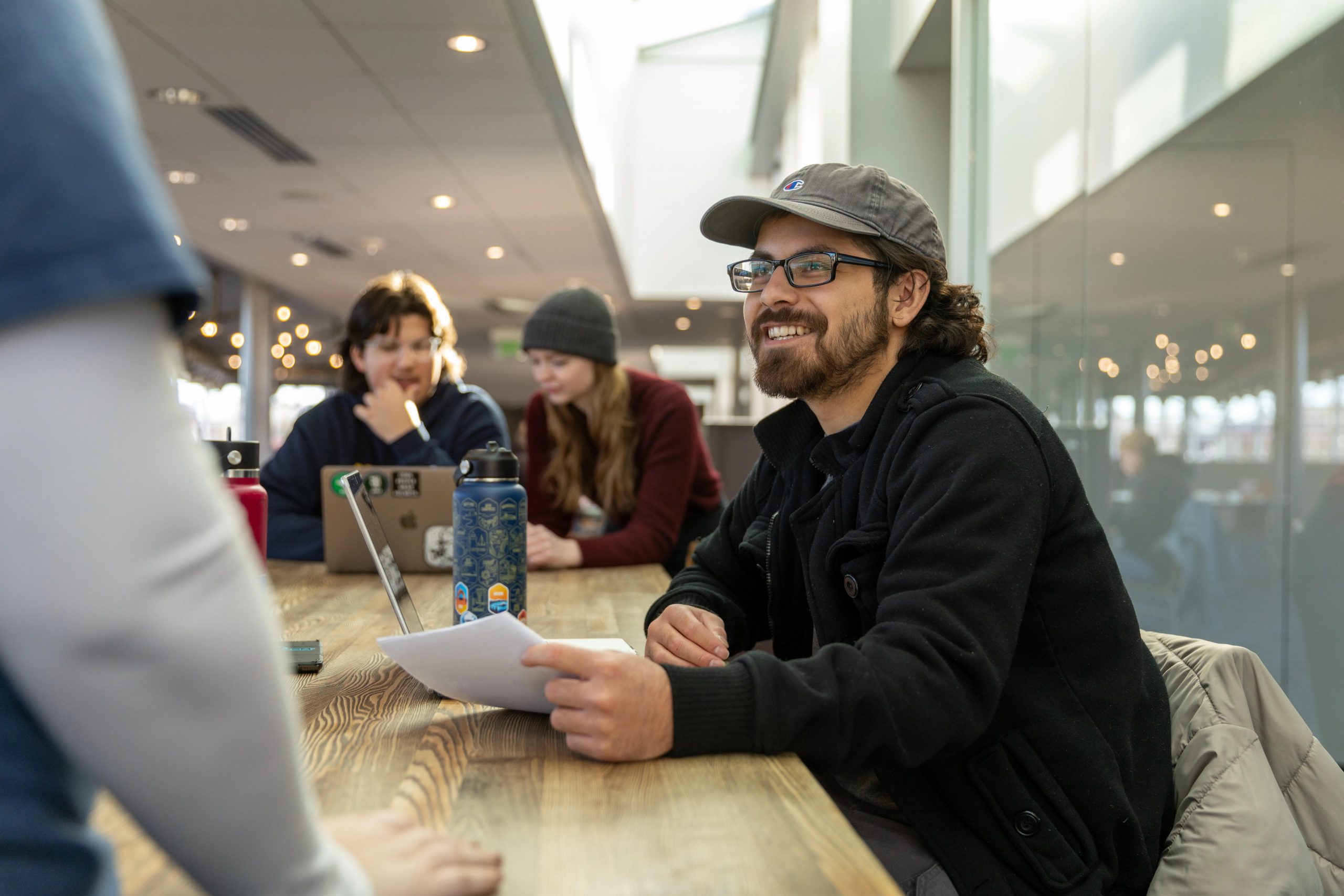 An N A U Online student studies with friends at a coffee shop.