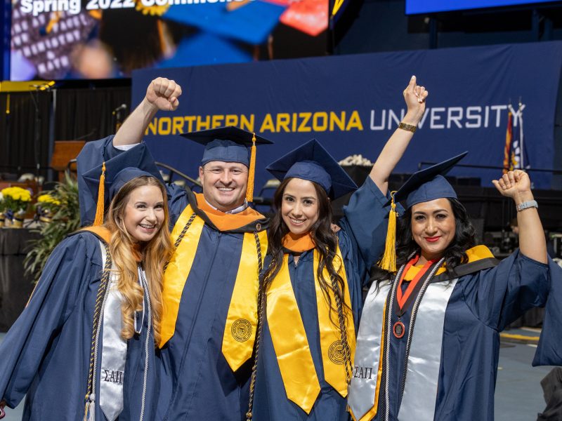 N A U students happily cheer at commencement.