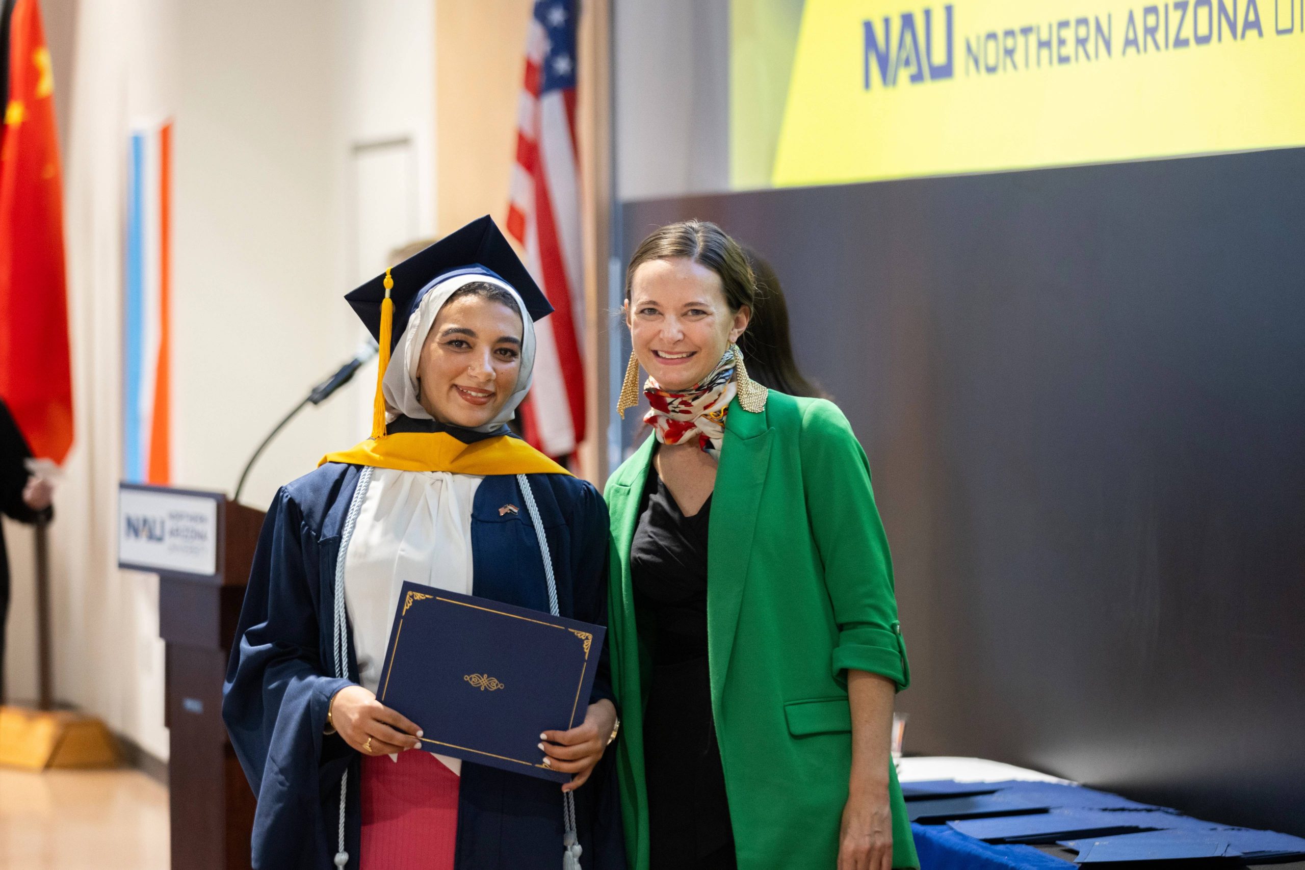 An N A U international student smiles and poses with faculty at commencement.