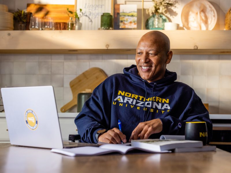 An N A U Online graduate student attends class from their kitchen table.