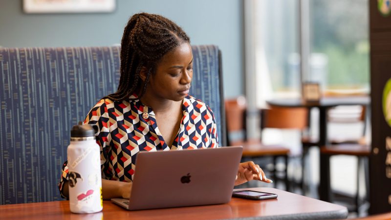 N A U student sitting at a table working on their laptop.