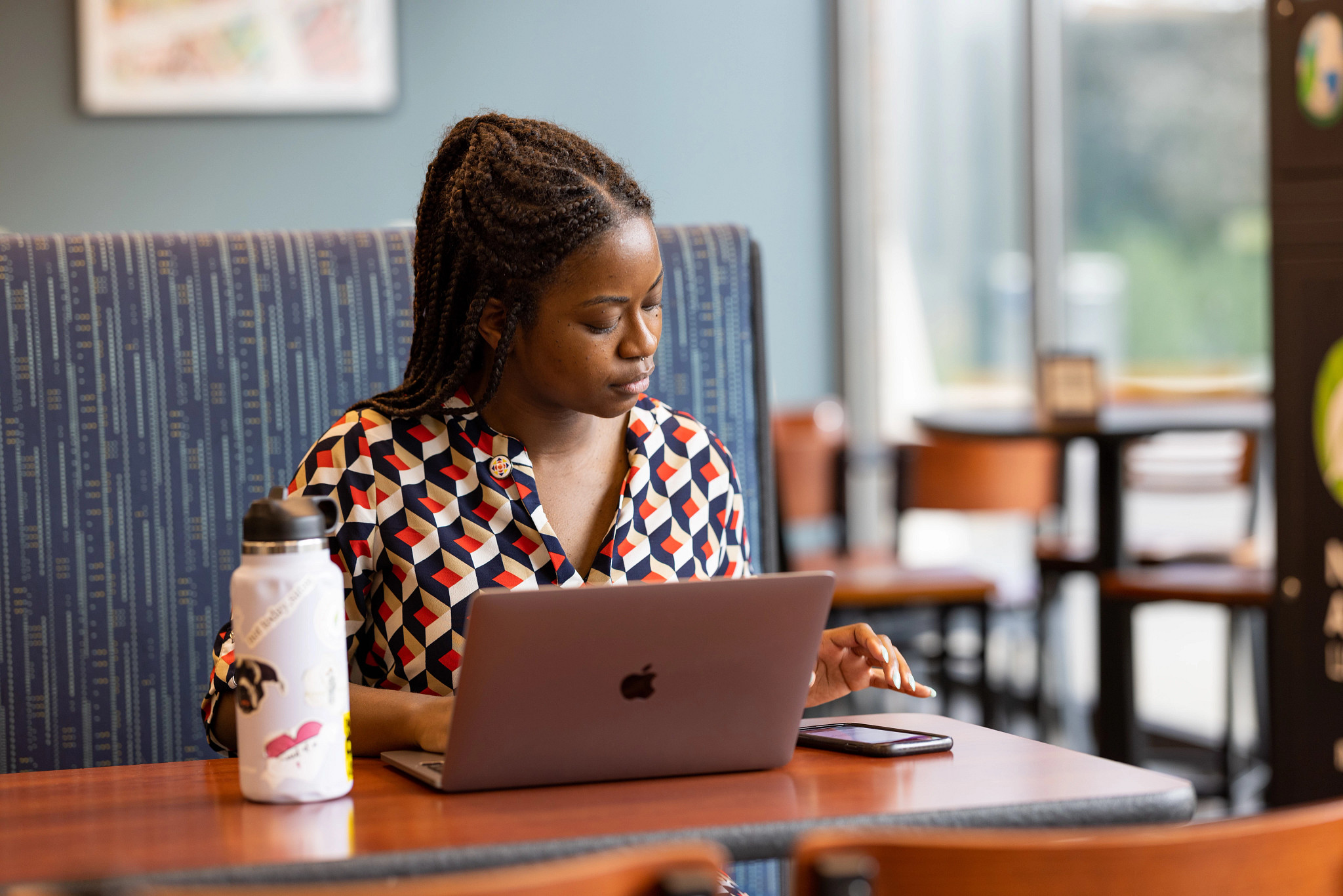 N A U student sitting at a table working on their laptop.